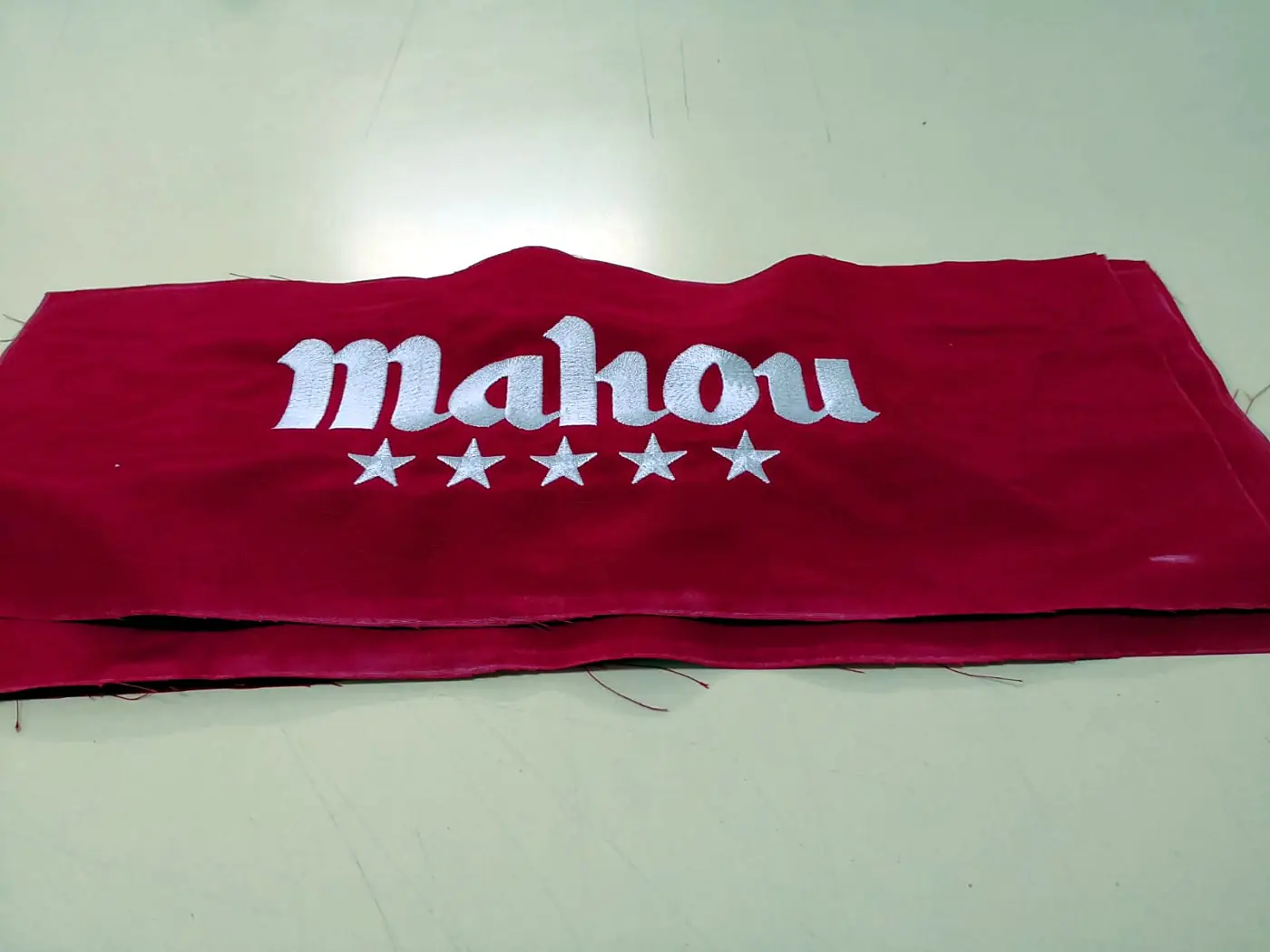 Logotipo bordado en blanco sobre tela roja