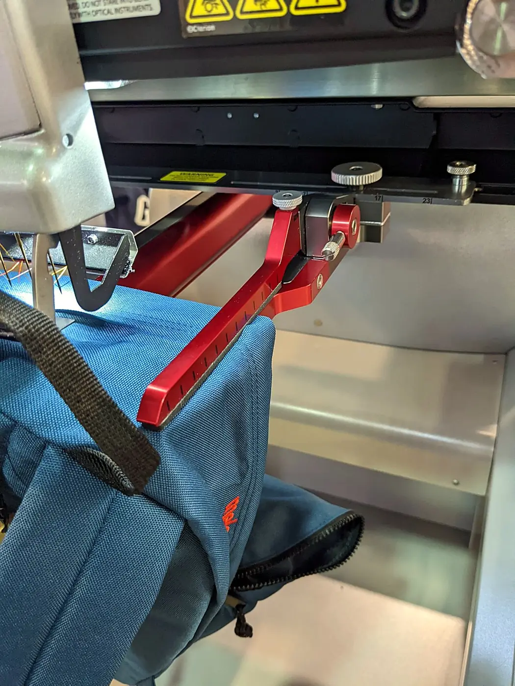 Mochila azul colocada en el bastidor de la máquina de bordar