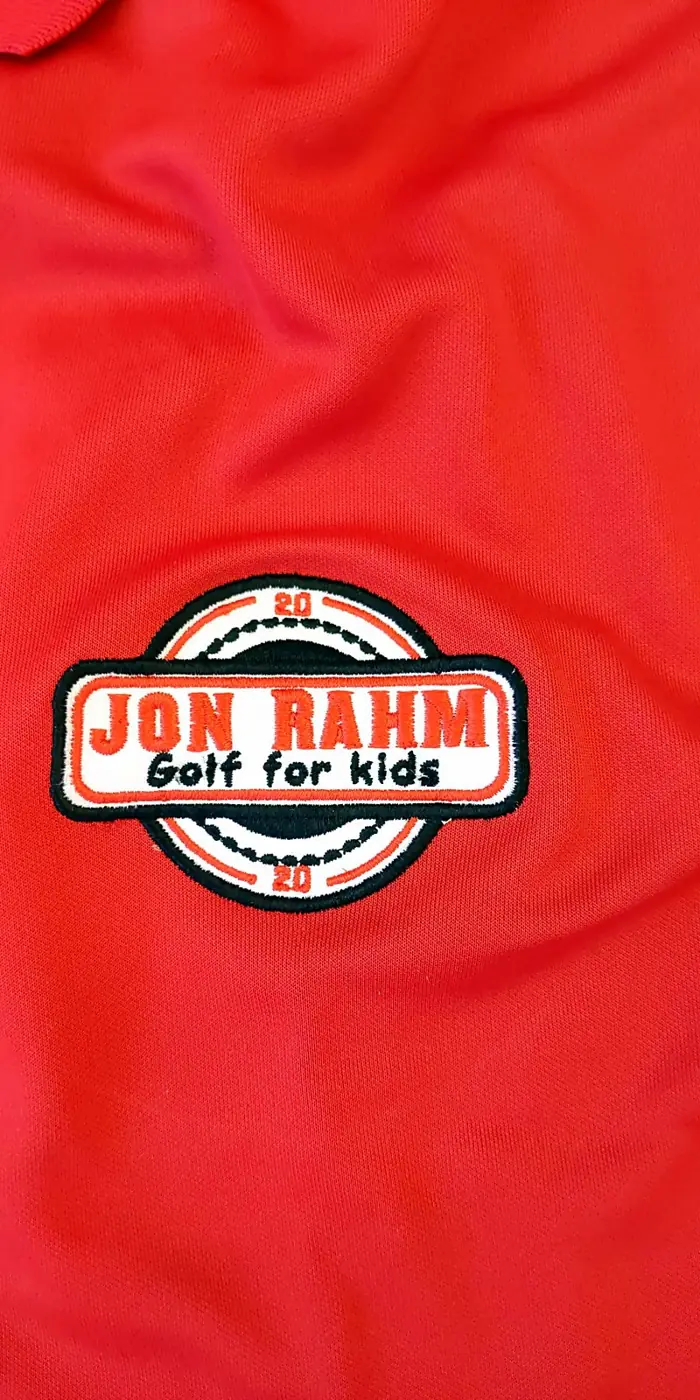 Parche bordado de una escuela de golf infantil en un polo rojo